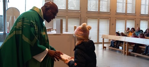 Pfarrer Charles Lwanga Mubiru übergab die gesegneten Kinderbibeln den Erstkommunionkindern (Foto: PAss. Peter Artl)